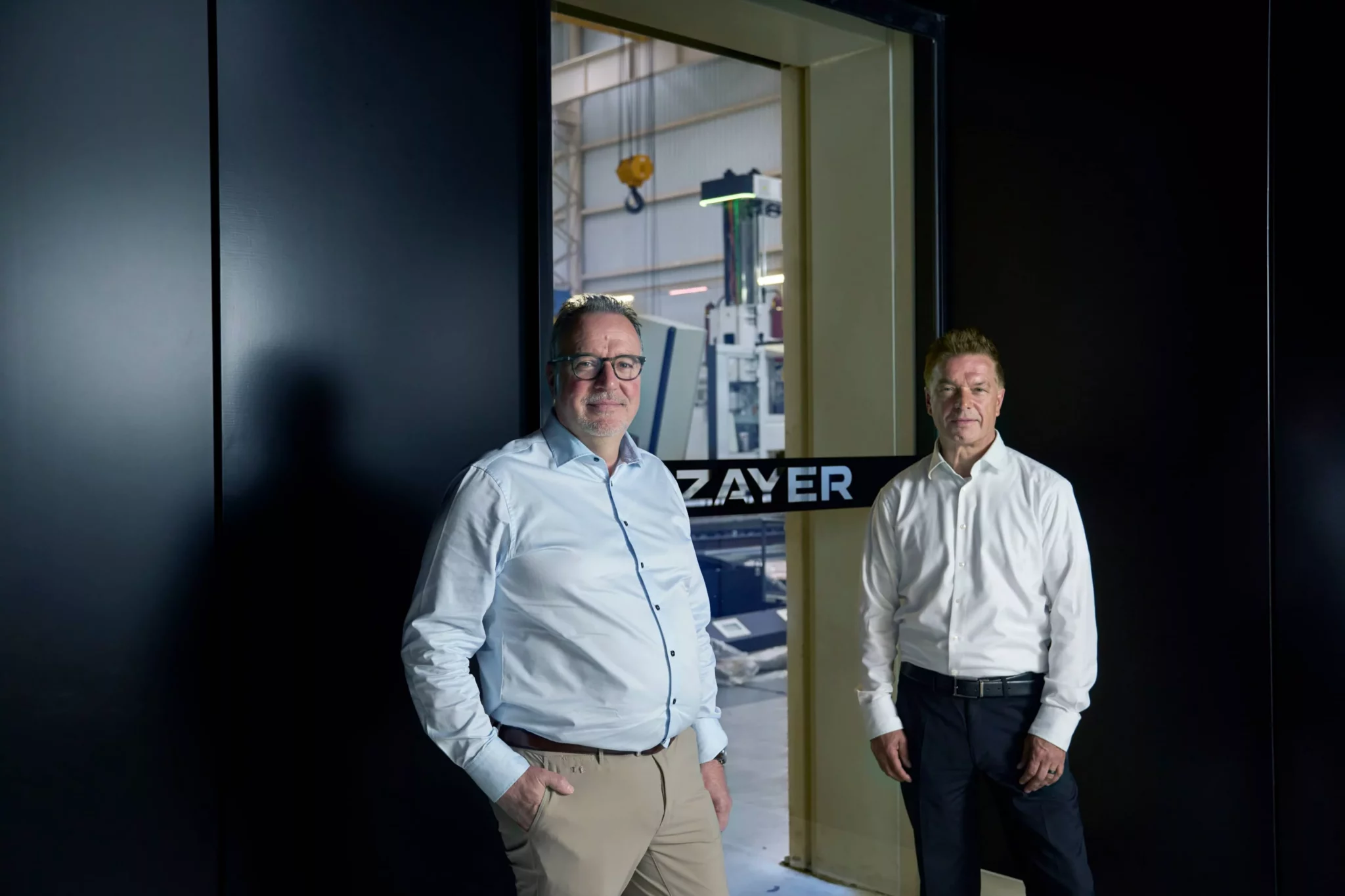 Zayer EMC mit zwei Managern vor CNC-Fräsmaschine im Werk.