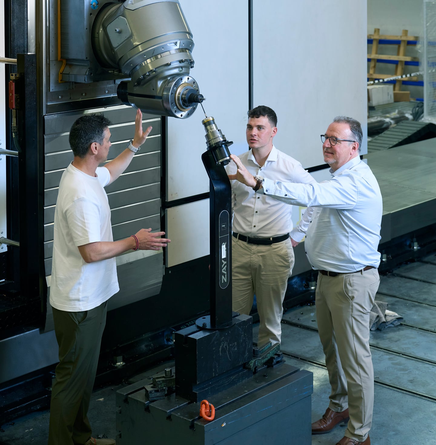 Drei Männer prüfen eine CNC-Fräsmaschine bei Zayer EMC.