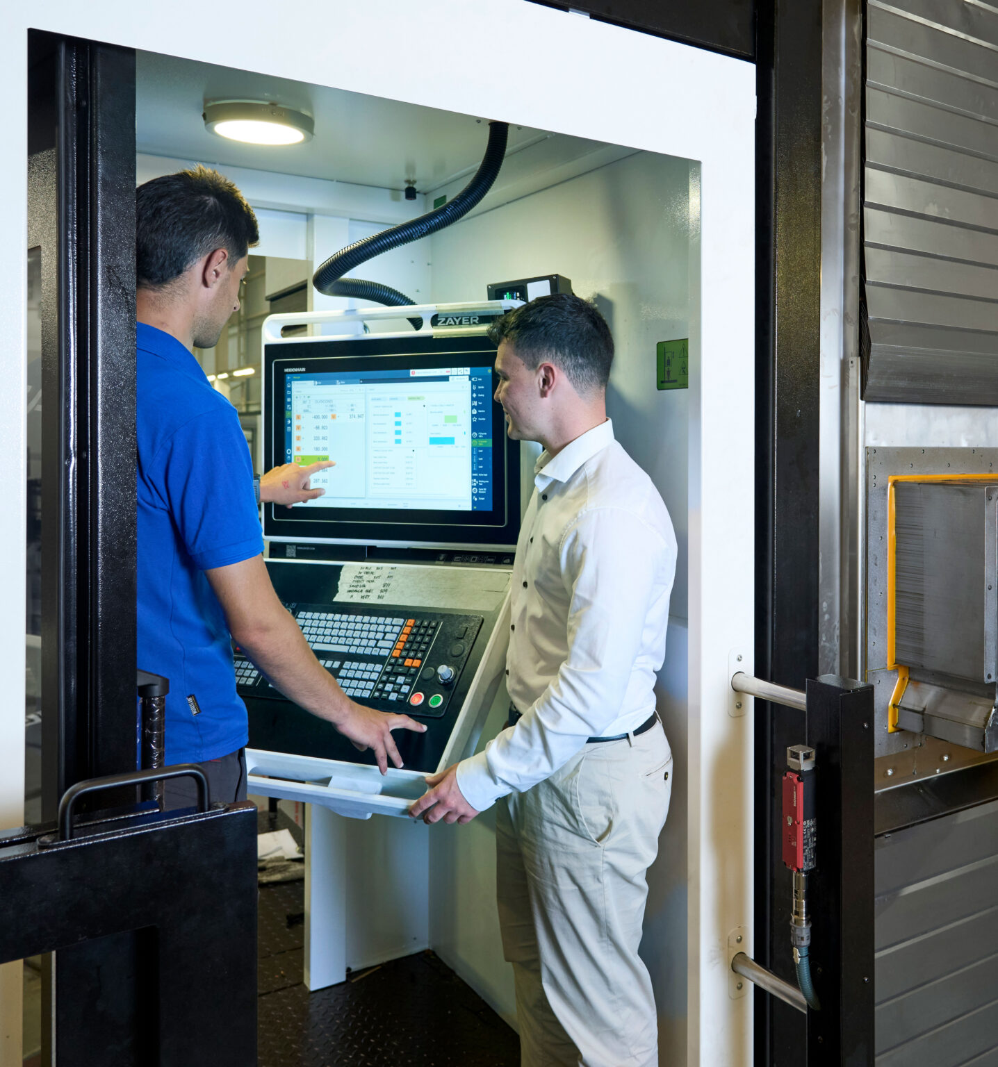 Zwei Techniker bei der Schulung an einer Zayer EMC CNC-Maschine.