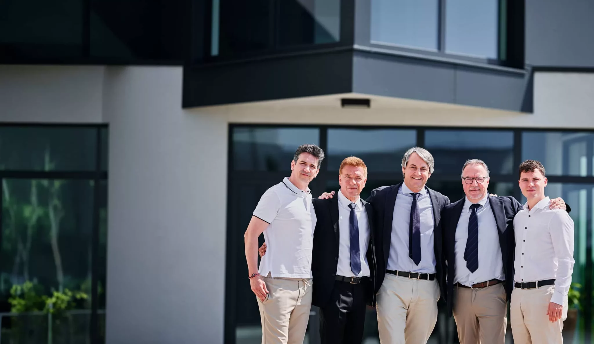 Fünf Mitarbeiter vor modernem Firmengebäude bei Zayer EMC.